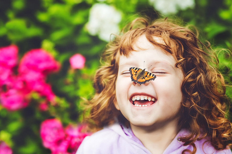 Schmetterling sitzt auf Nase eines Mädchens